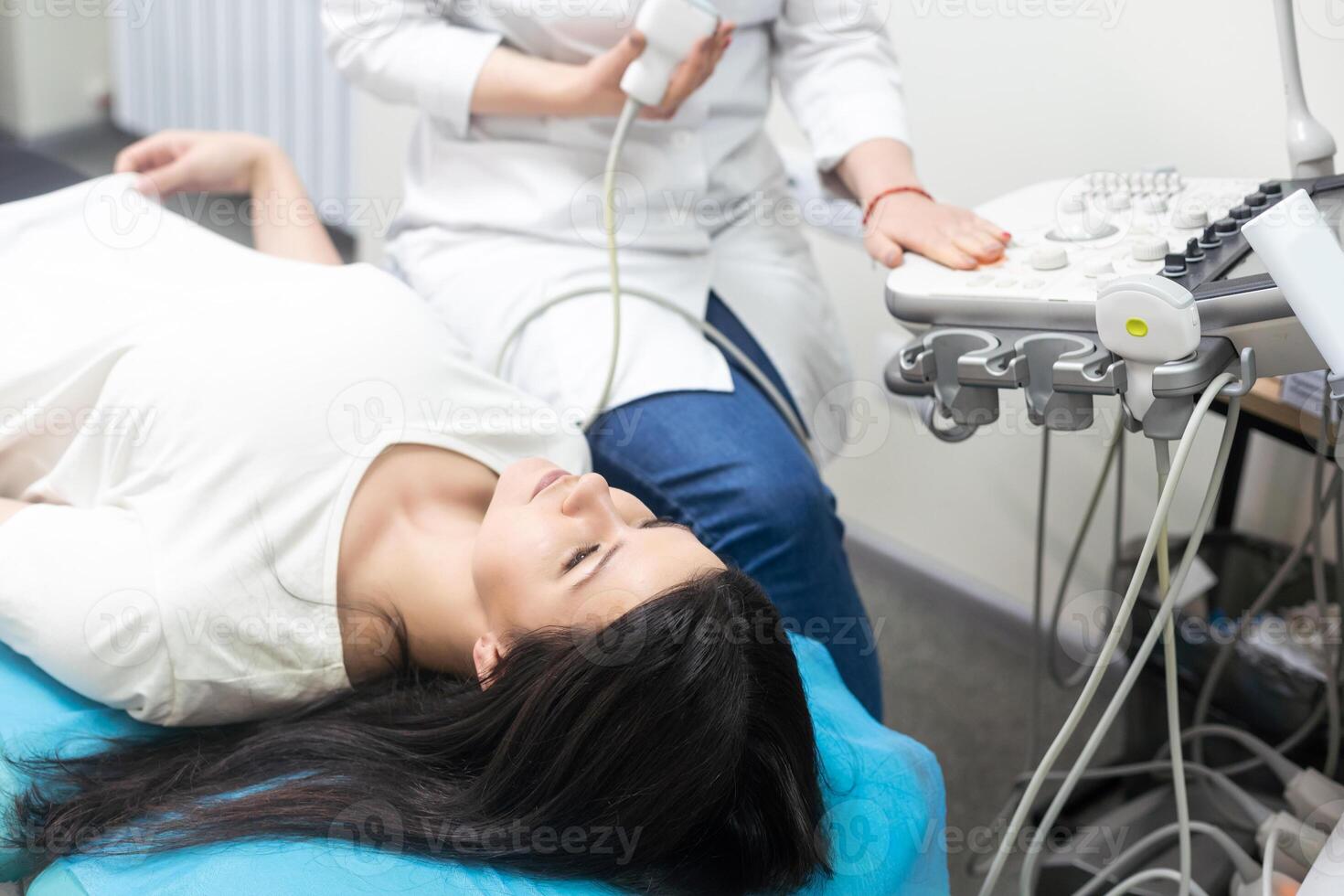 Ultrasound scanning diagnostic of woman thyroid gland in clinic, doctor runs ultrasound sensor photo