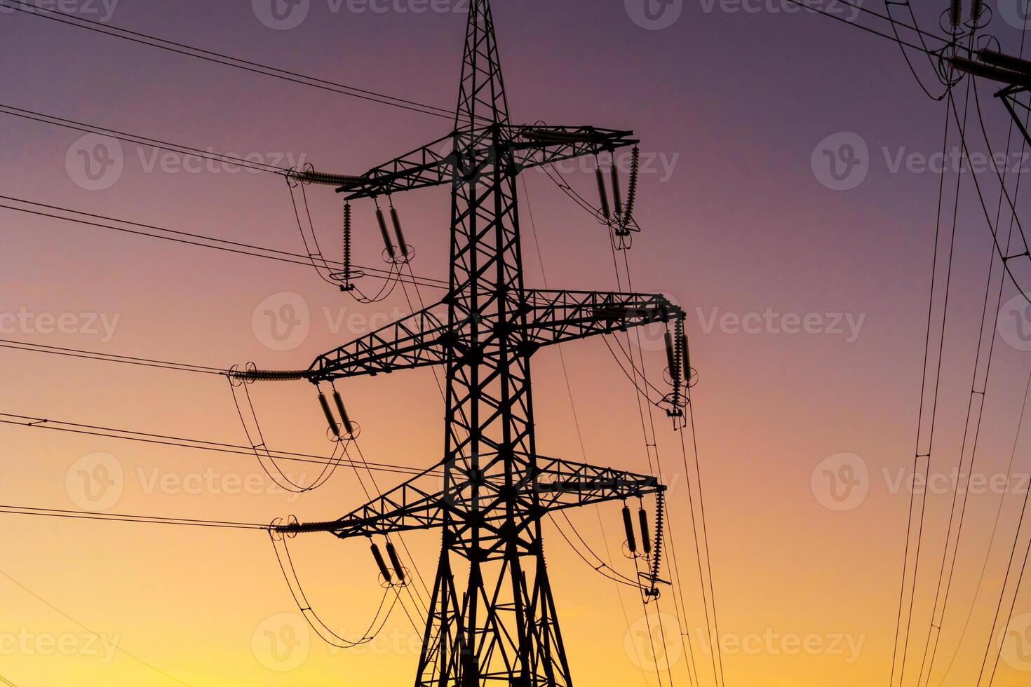 Energy Distribution Network - Electricity Pylons against Orange and Yellow Sunset. Closeup photo