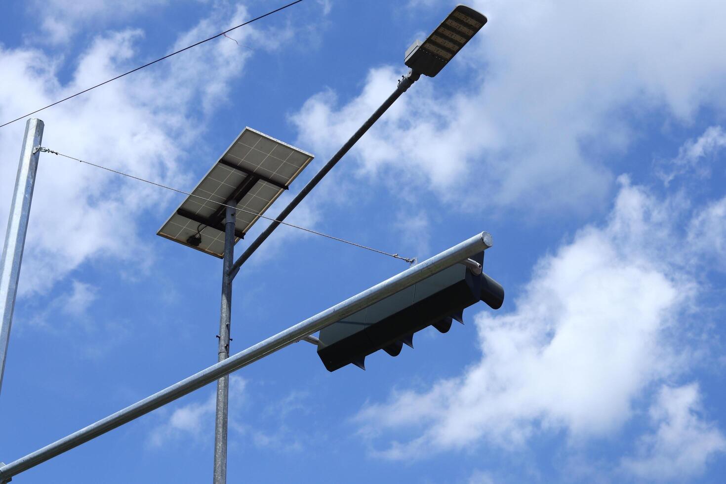 close-up photo of traffic control lights and street lighting based on solar panels isolated on blue sky background