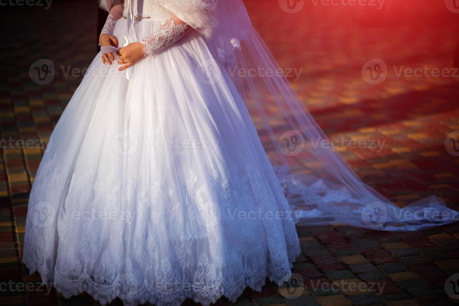 Beautiful white wedding gown dress with laces of a young bride on the pavement background isolated. Sweet romantic woman walking alone. Bridal concept photo