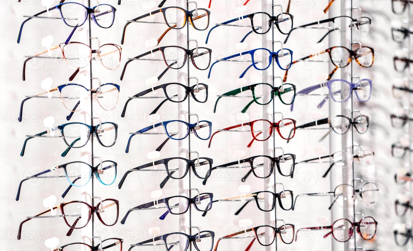 exhibition of glasses at shelves. Fashionable spectacles shown on a wall at the optical shop. Closeup. photo