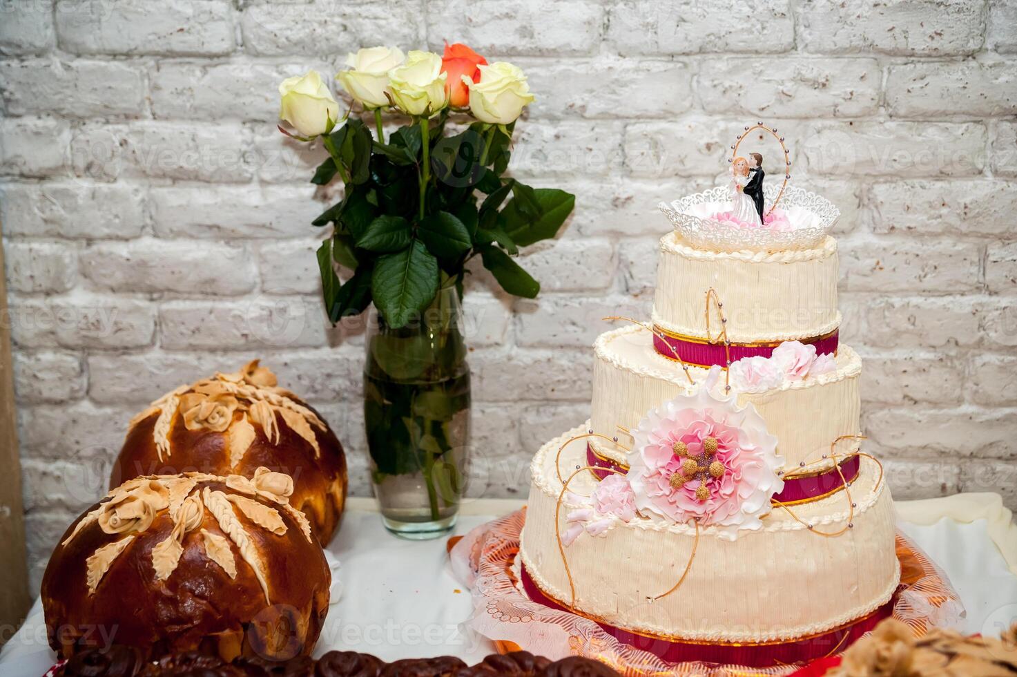 White wedding cake with flowers and special ceremony bread or loaf. Wedding concept. Closeup. photo