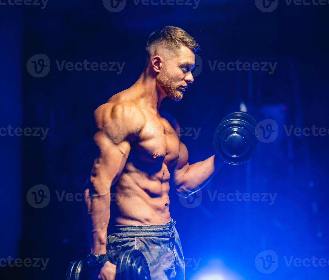 Athlete with strong body doing work out pushing up excercise in gym. View from the side. Blue light filter. photo