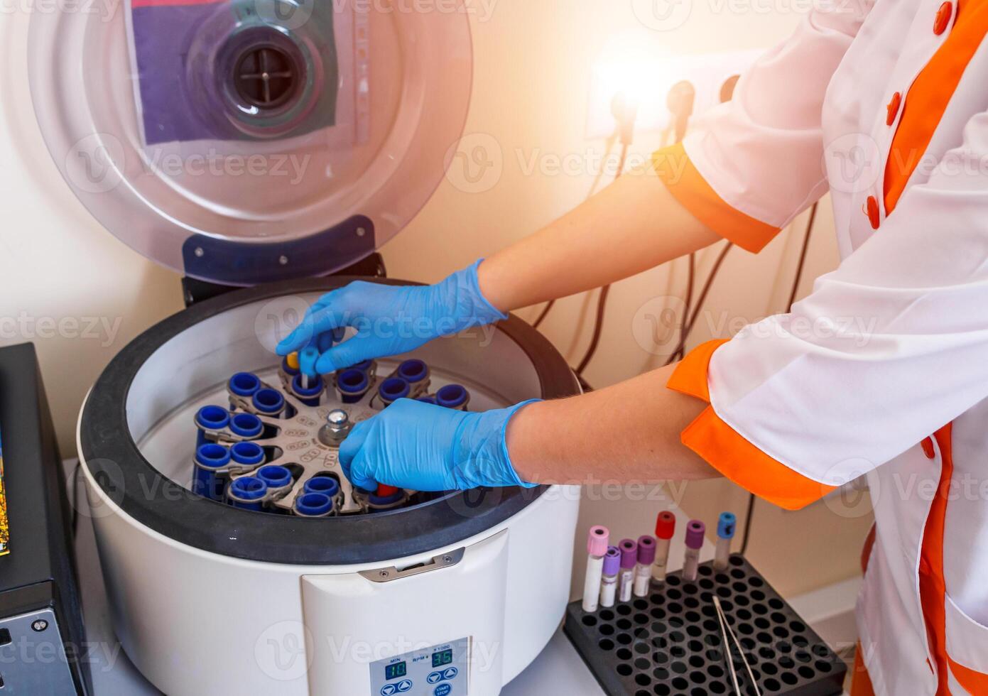 Women's hands in blue gloves putting blood samples into a centrifuge in laboratory. photo