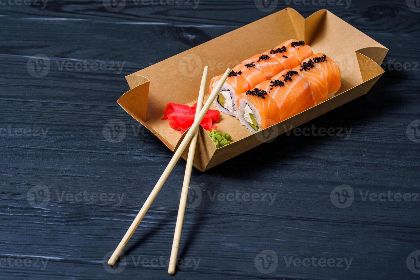 Traditional Japanese food. Sushi, rolls and chopsticks for sushi on a dark background. Rolls in box to go. photo
