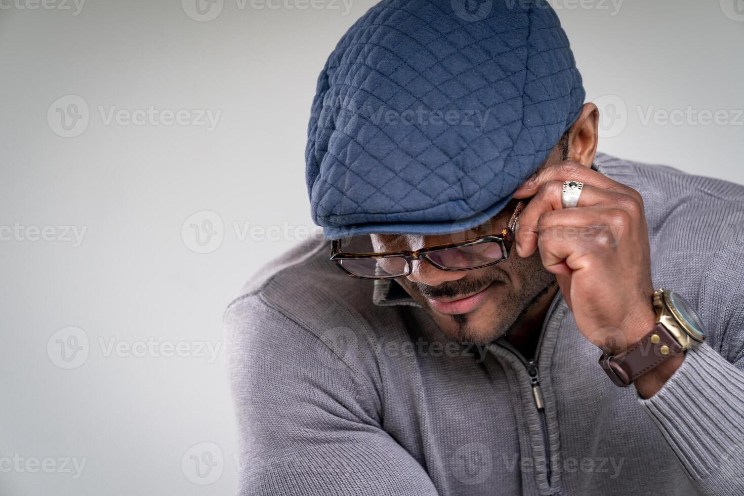 Fashionable man in hat and glasses posing for camera. Attractive handsome male looking down. photo