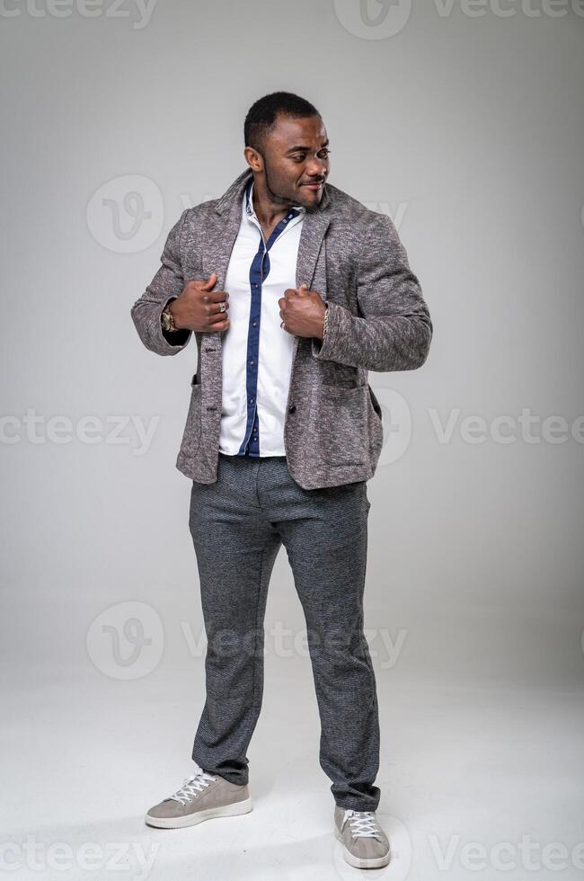 African amercan man standing and looking away. Handsome businessman posing and holding his fashionable jacket. Full-lenght photo. photo