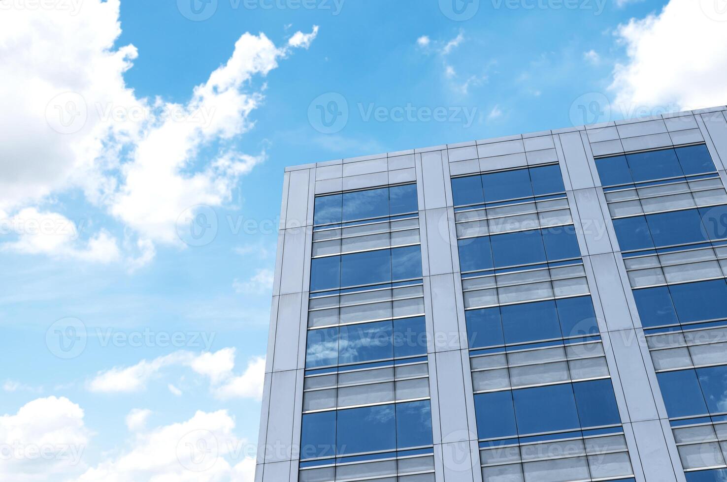 Bottom up view modern office building with glass window on blue sky background photo