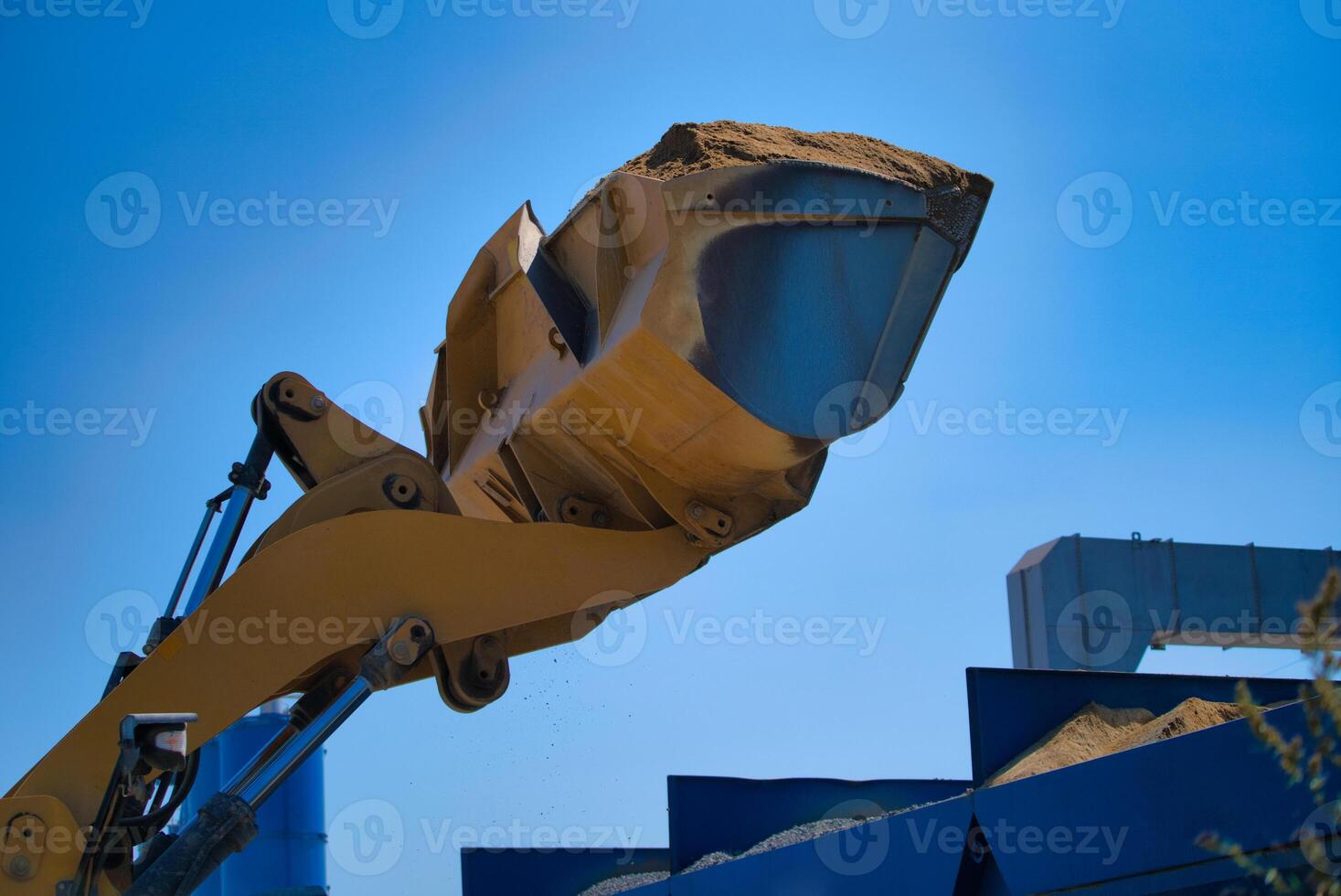 Yellow excavator on a construction site against blue sky photo