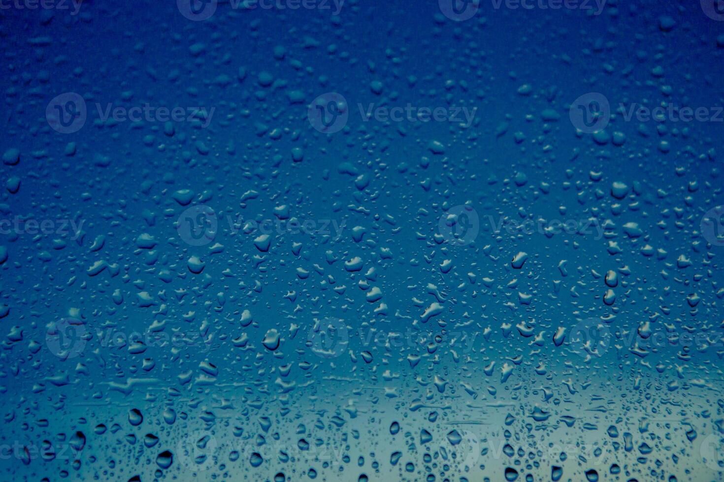 raindrops flow down the window of a house on the background of a blue sky. Close-up photo