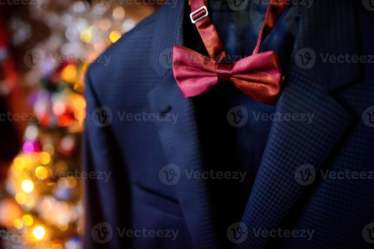 Dark blue wedding suit and wine-colored bow-tie on blurred background. Butterfly necktie on the man's costume. Close-up photo