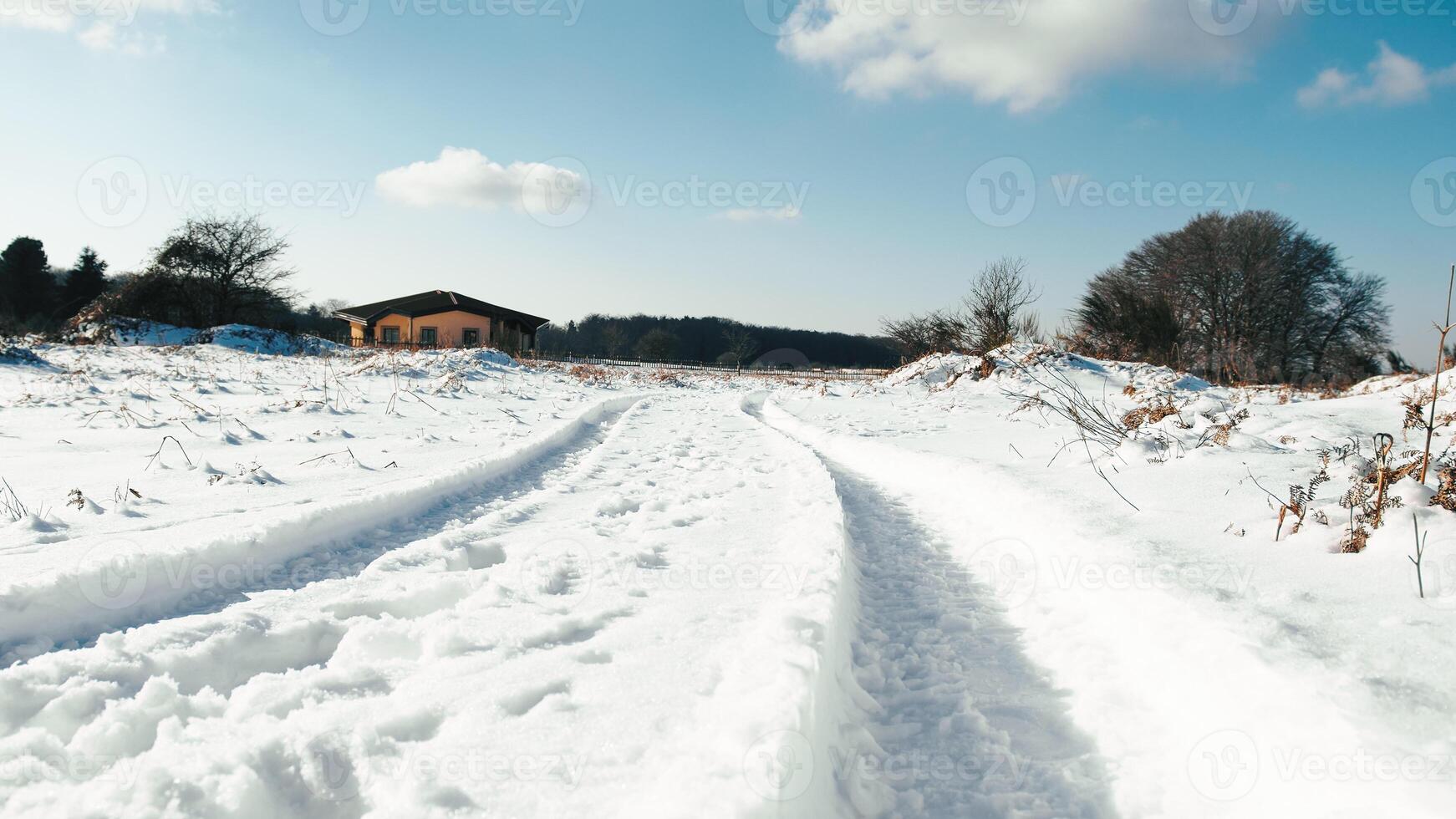 small house surrounded by snow with vehicle traces photo