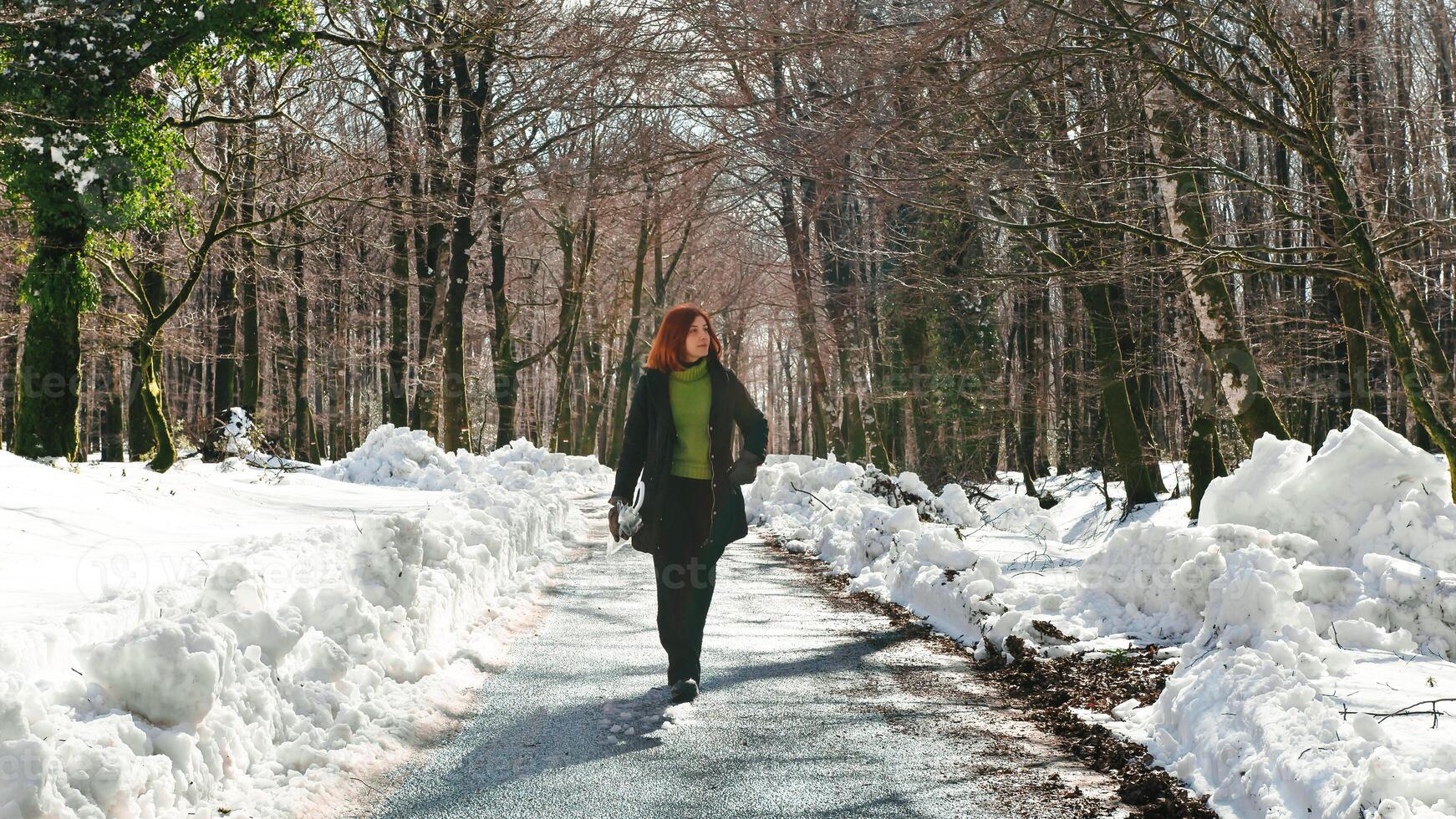 joven mujer caminando en un Nevado calle con un paraguas foto