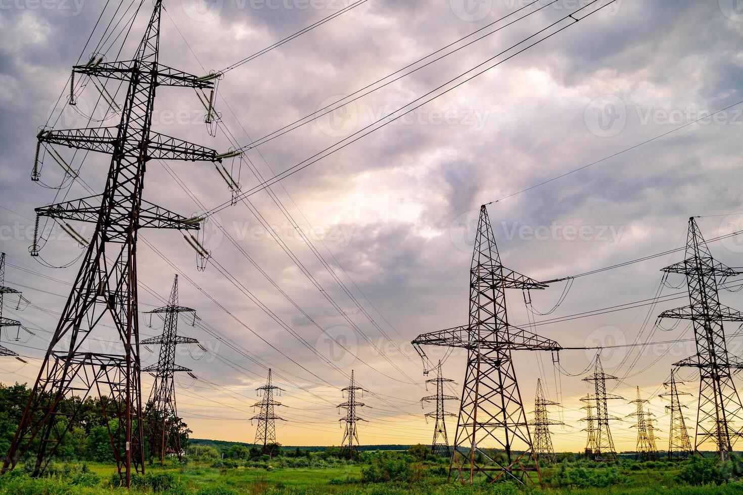 Electricity pylons and high-voltage power lines on the green grass. Power plant. Electrical power grid. View from below. photo