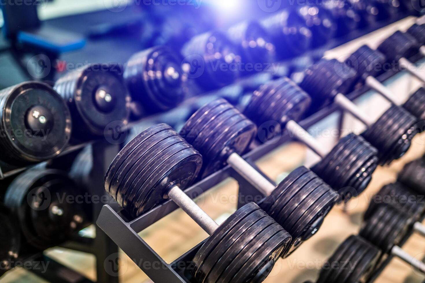 Rows of dumbbells in the gym with blurred background. Closeup. Sport equipment. Healthy life concept. photo