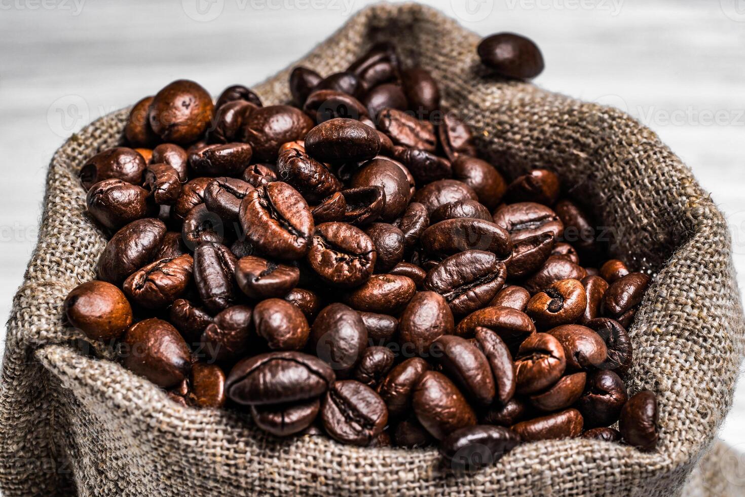 Brown roasted coffee beans in the sackon the blurred background. The bag full of fresh coffee grains. Close-up photo