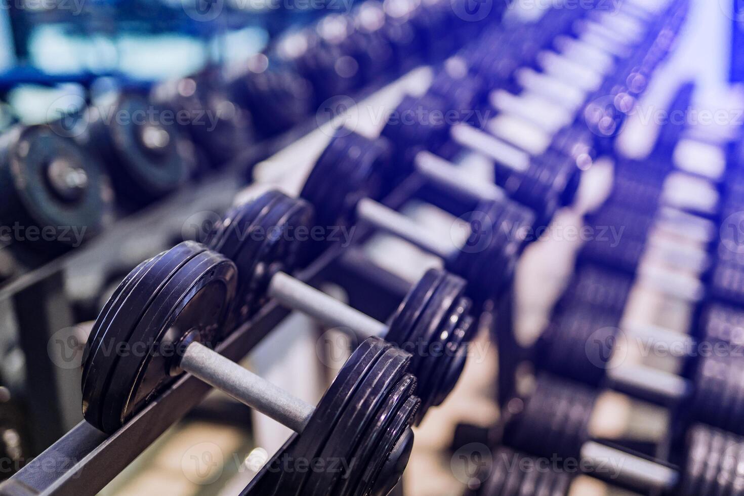 Rows of dumbbells on racks in the sport club. Weight Training Equipment. Image of iron dumbbells. Close-up photo