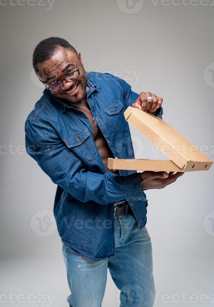 hermoso hombre abierto Pizza caja. contento emocionado hombre mirando dentro cámara con Pizza en manos. lleno de alegría mensajero. foto