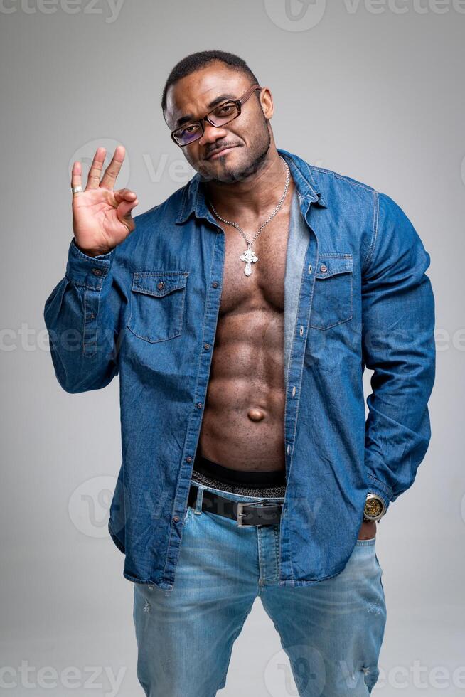 Fashionable muscular man looking into camera. Athletic male in glasses posing at studio. photo