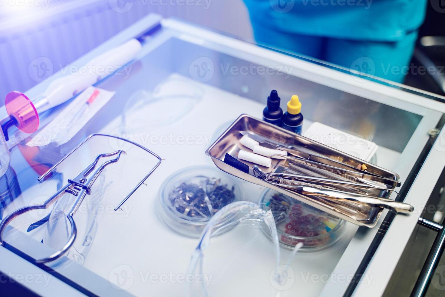 Small glass table with dentist tools and protective glasses in stomatology clinic. Sterile instruments on the table in dentist's office. Close-up photo