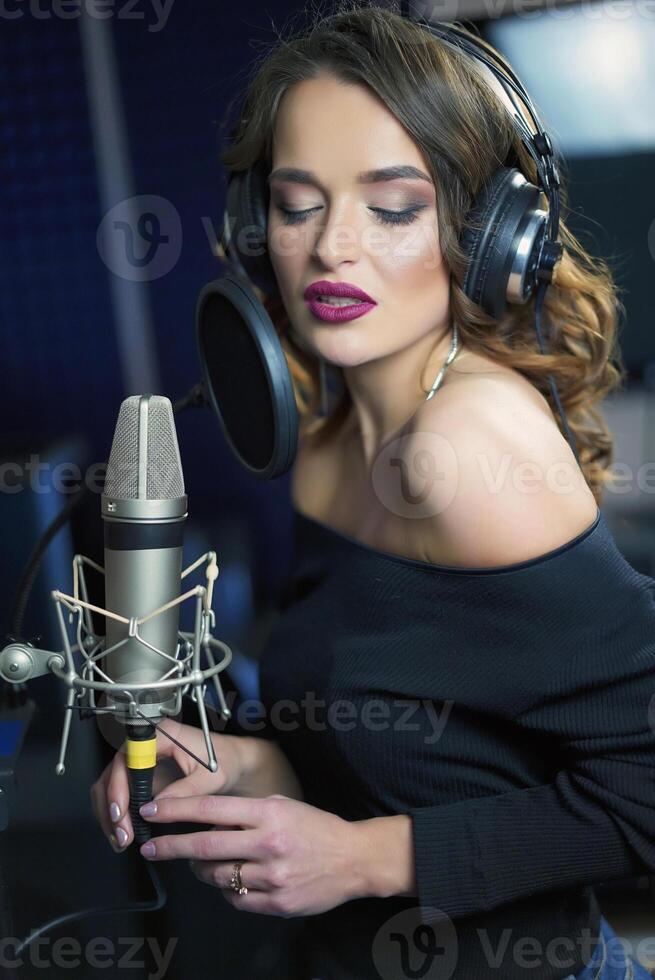 joven hembra cantante grabación álbum en el profesional estudio. mujer canto un canción en música grabación estudio. foto