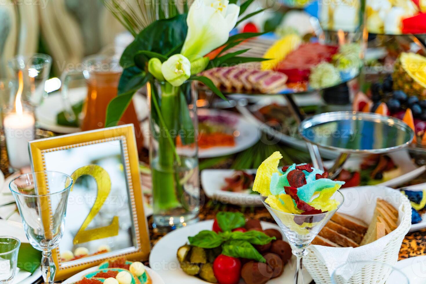 Festively served table with different food, decorated with flowers for banquet, restaurant interior. Plenty of tasty food for guests. photo