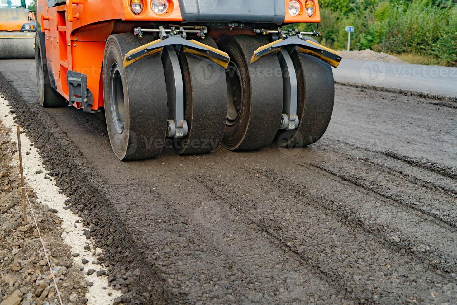 Roller machine works on asphalt. Close up view of the road roller working on the new road construction site photo