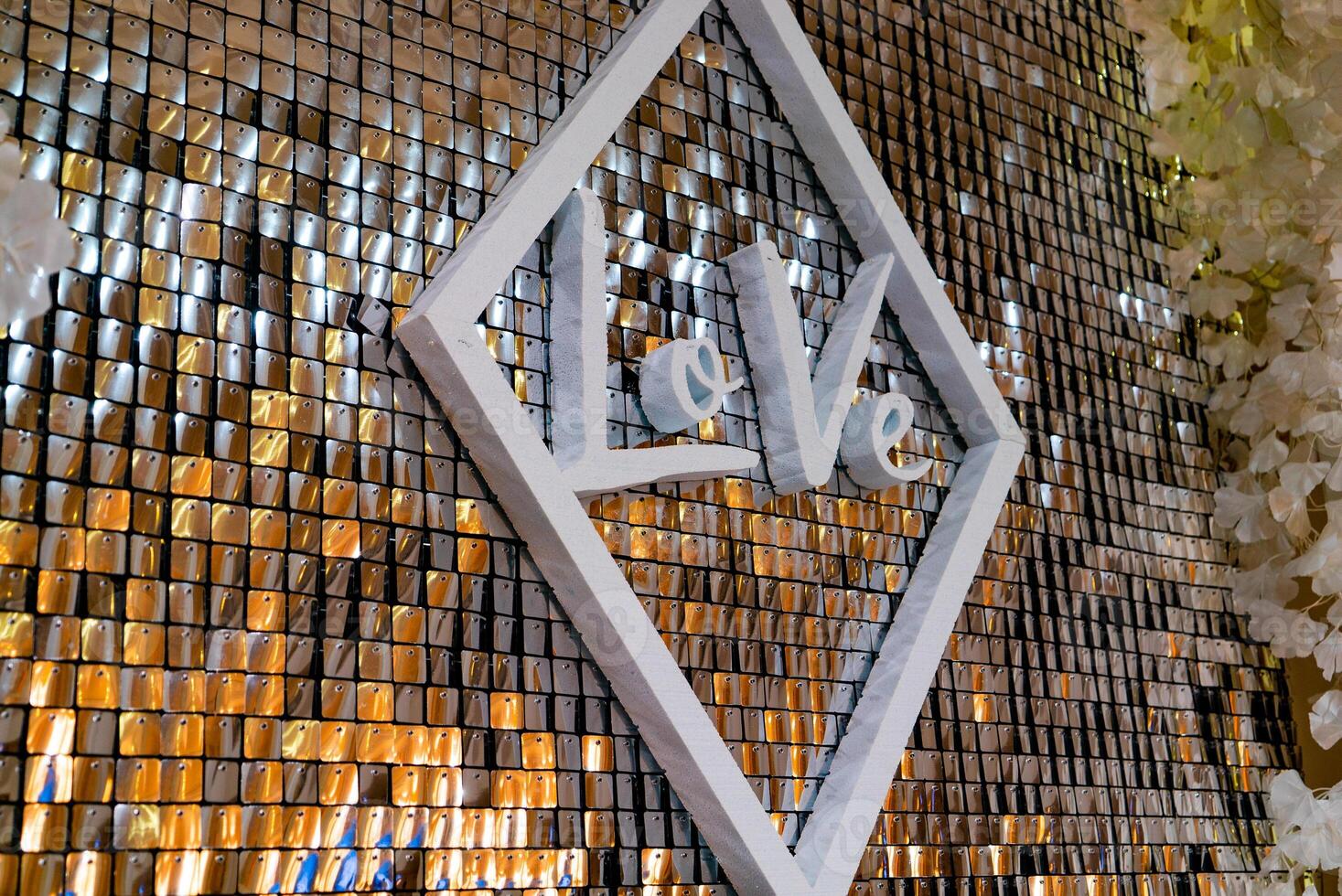 decorated wall in the form of gold squares and with a white inscription in a rhombus is at the wedding in the cafe. Close-up photo