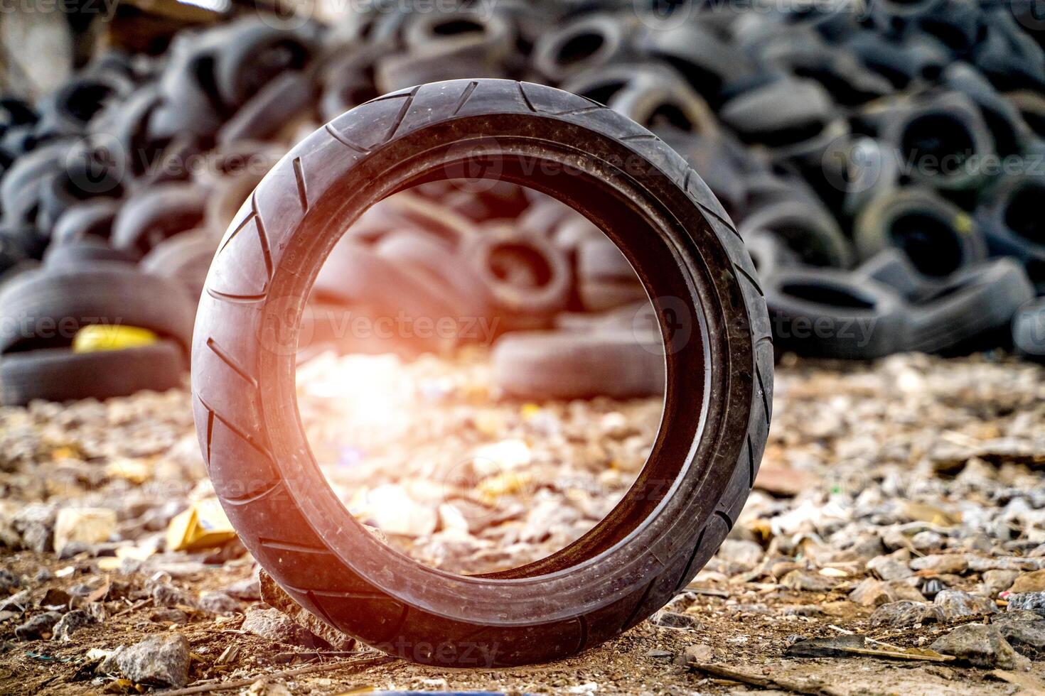 Old worn and dirty car tire. Small dirty old tire and used tires pile in dump at background photo
