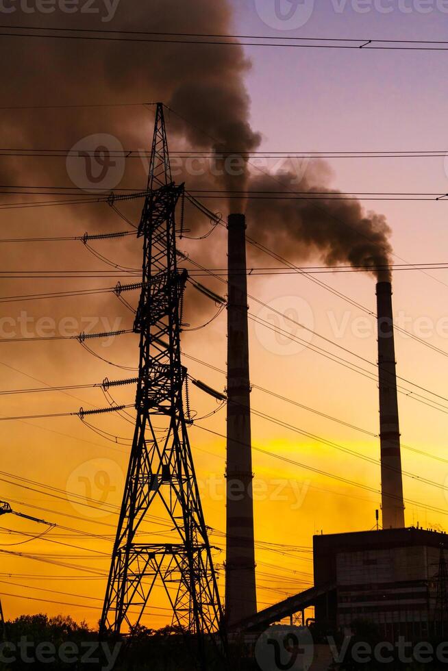 high voltage post. High-voltage tower sky background, factory pipe with smoke over it. Earth pollution concept. Industrialisation. Selective focus photo