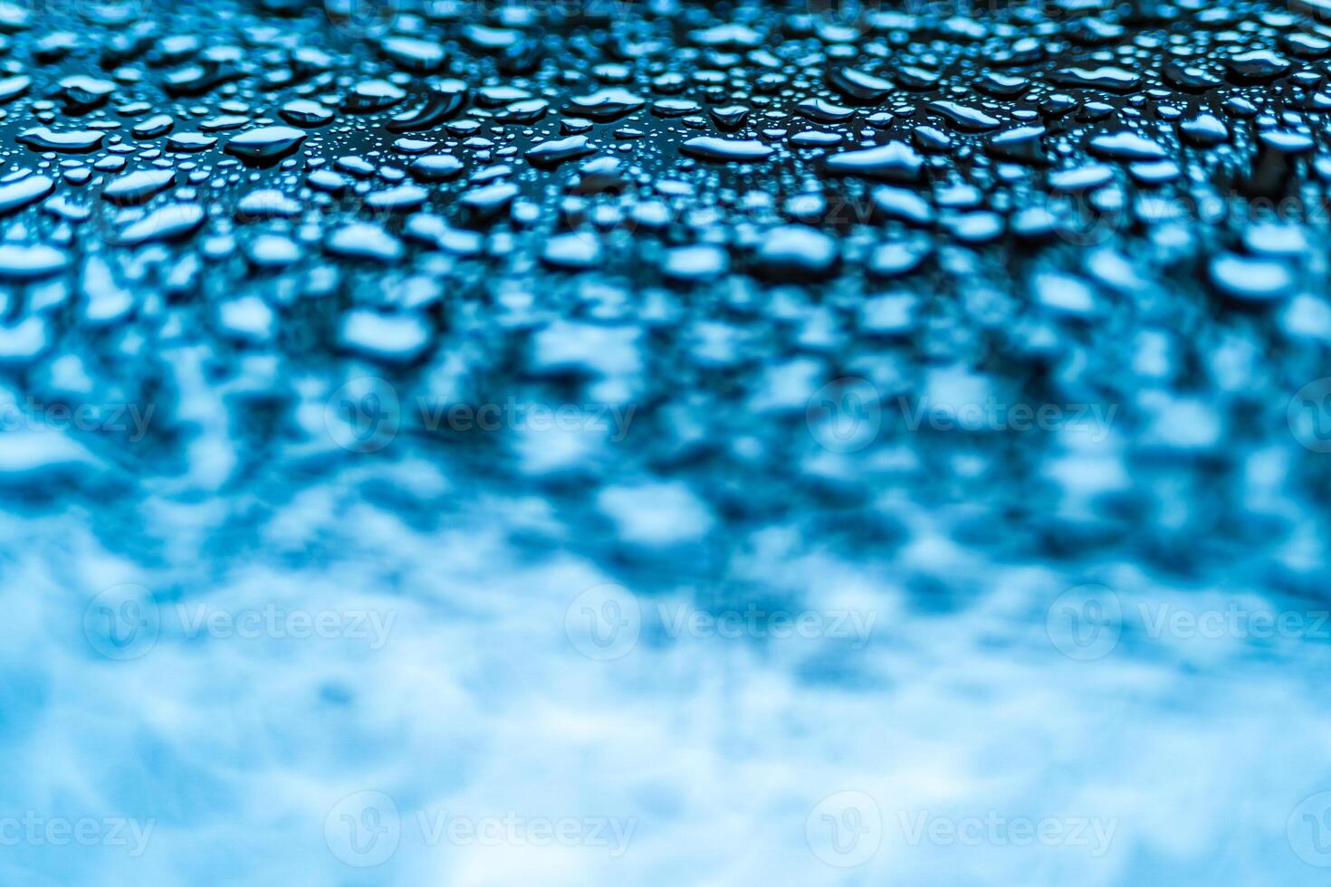 Realistic blue water droplets condensed for creative design on a glass. Clear aqua drops of different form above in the photo and blurred below.Macro shot