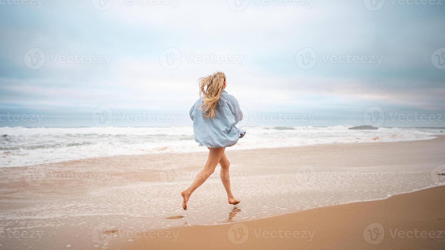 Woman running on sandy sea beach during summer vacation photo