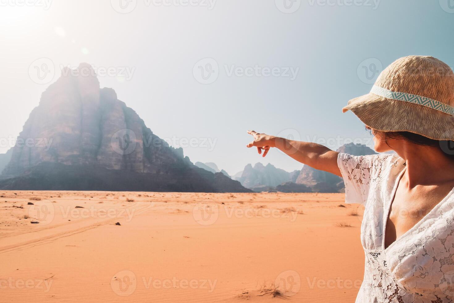 Back view female tourist stand watch point finger to seven pillars of wisdom monument in wadi rum desert-famous nature reserve in middle east. Explore Jordan banner photo
