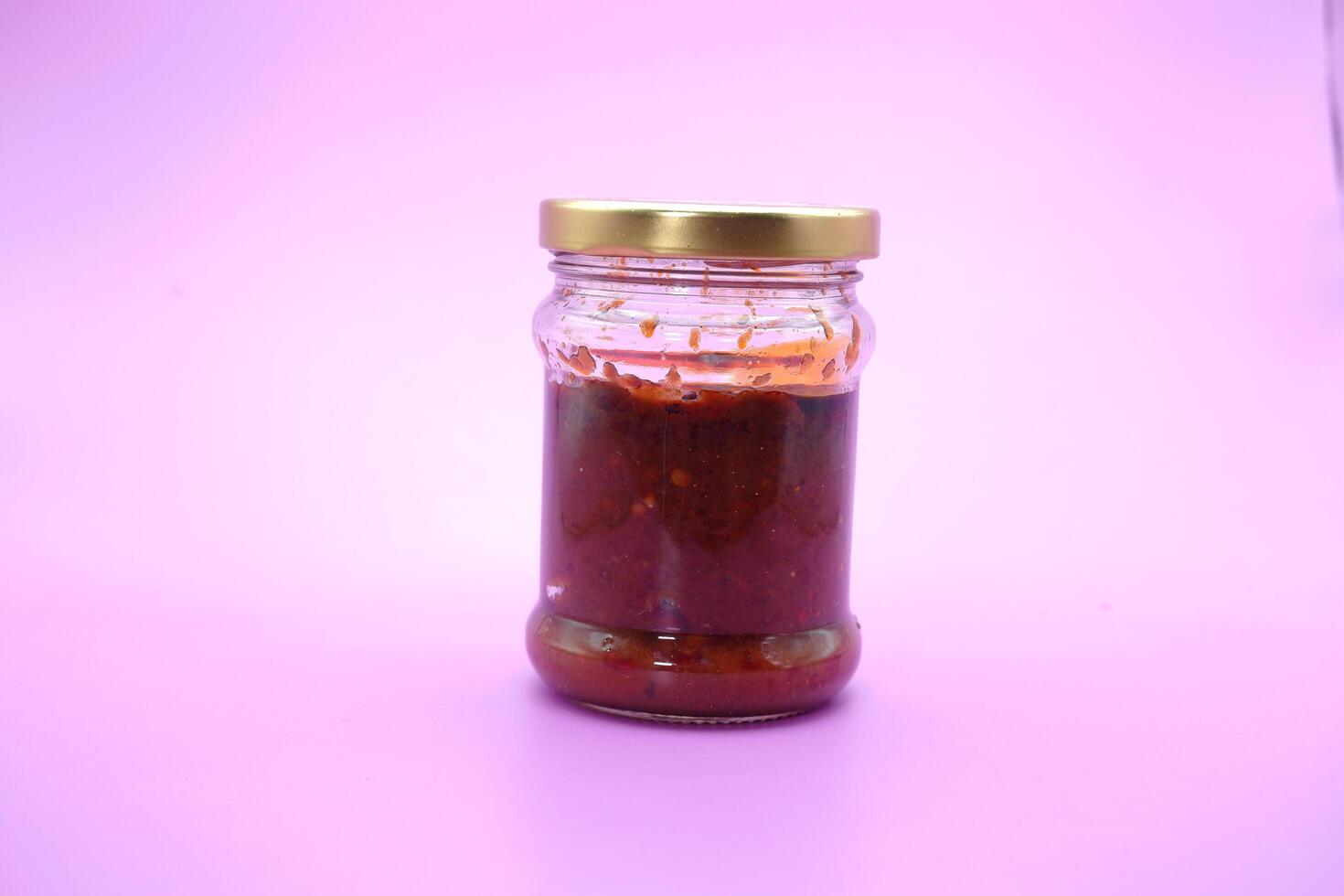chile salsa en un vaso botella. chile salsa aislado en un púrpura antecedentes. foto
