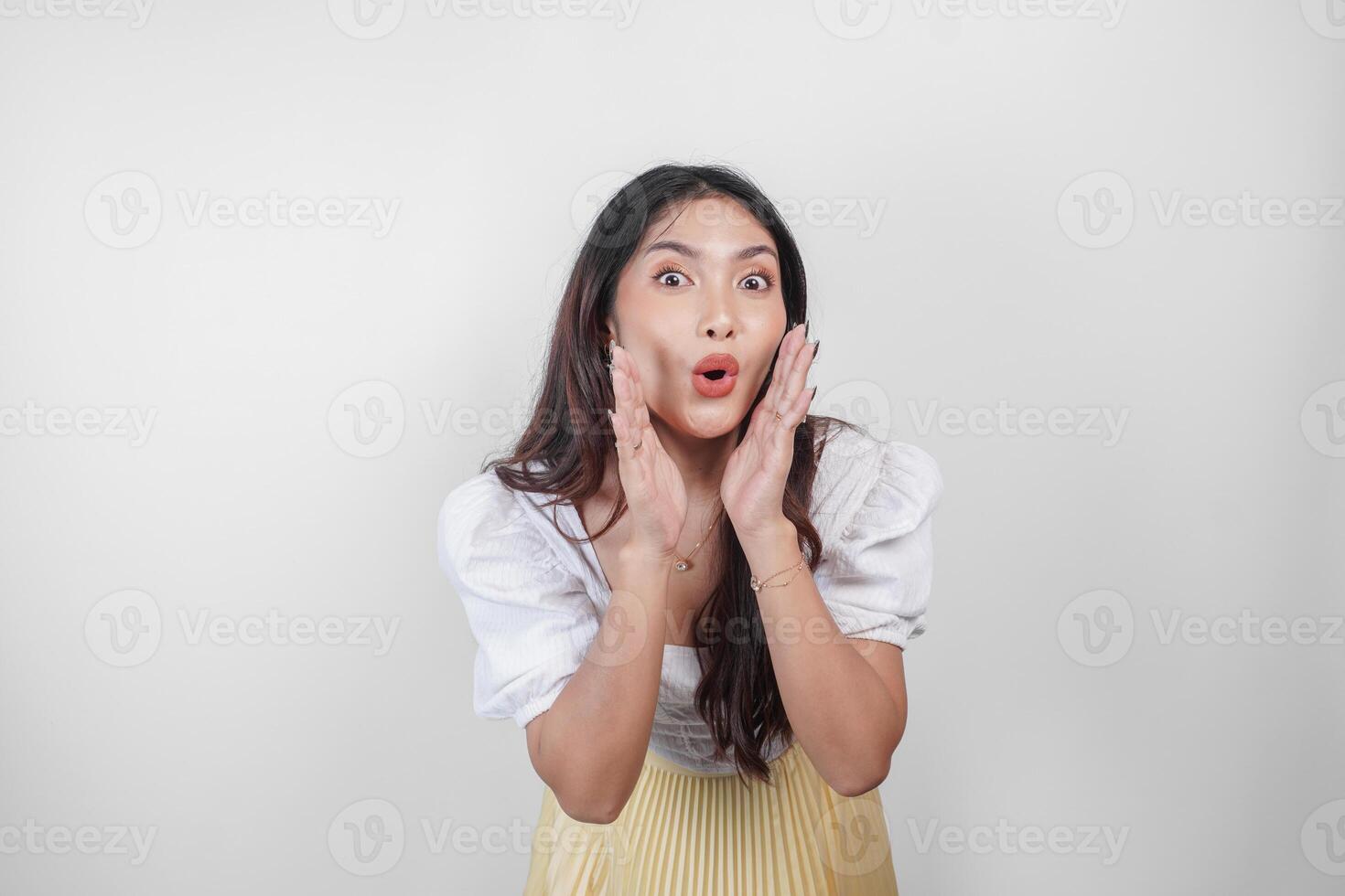 A young beautiful Asian woman is shouting and screaming loud with a hand on her mouth, isolated by white background. photo