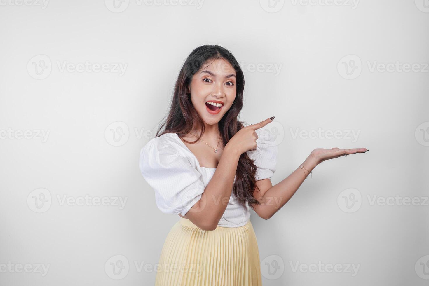 A cheerful Asian woman is pointing copy space beside her, isolated by white background. photo