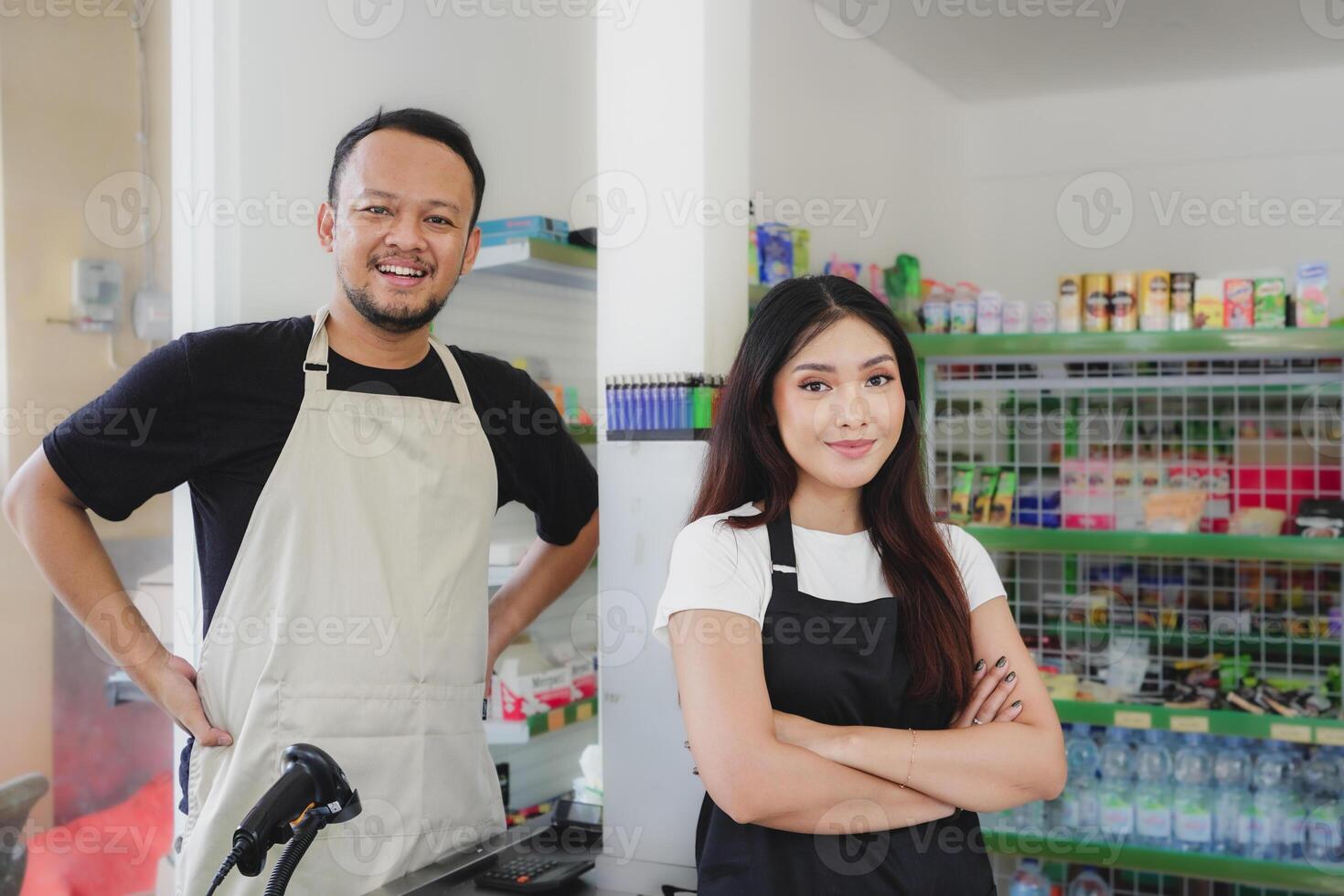 Confident young Asian people as convenience store staff in apron standing with arms crossed smiling to camera. photo