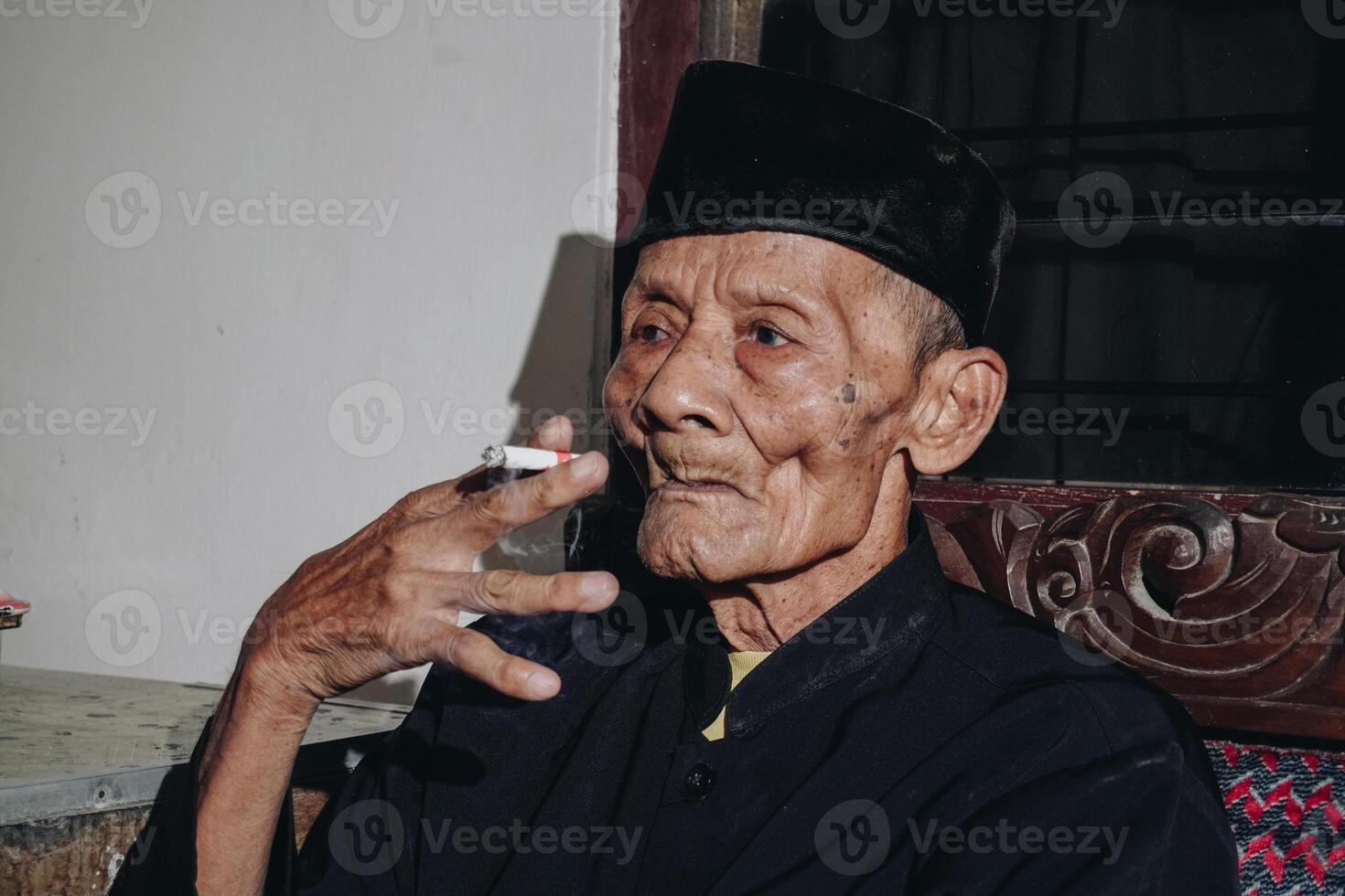 Portrait of an elderly Asian man smoking a cigarette. photo