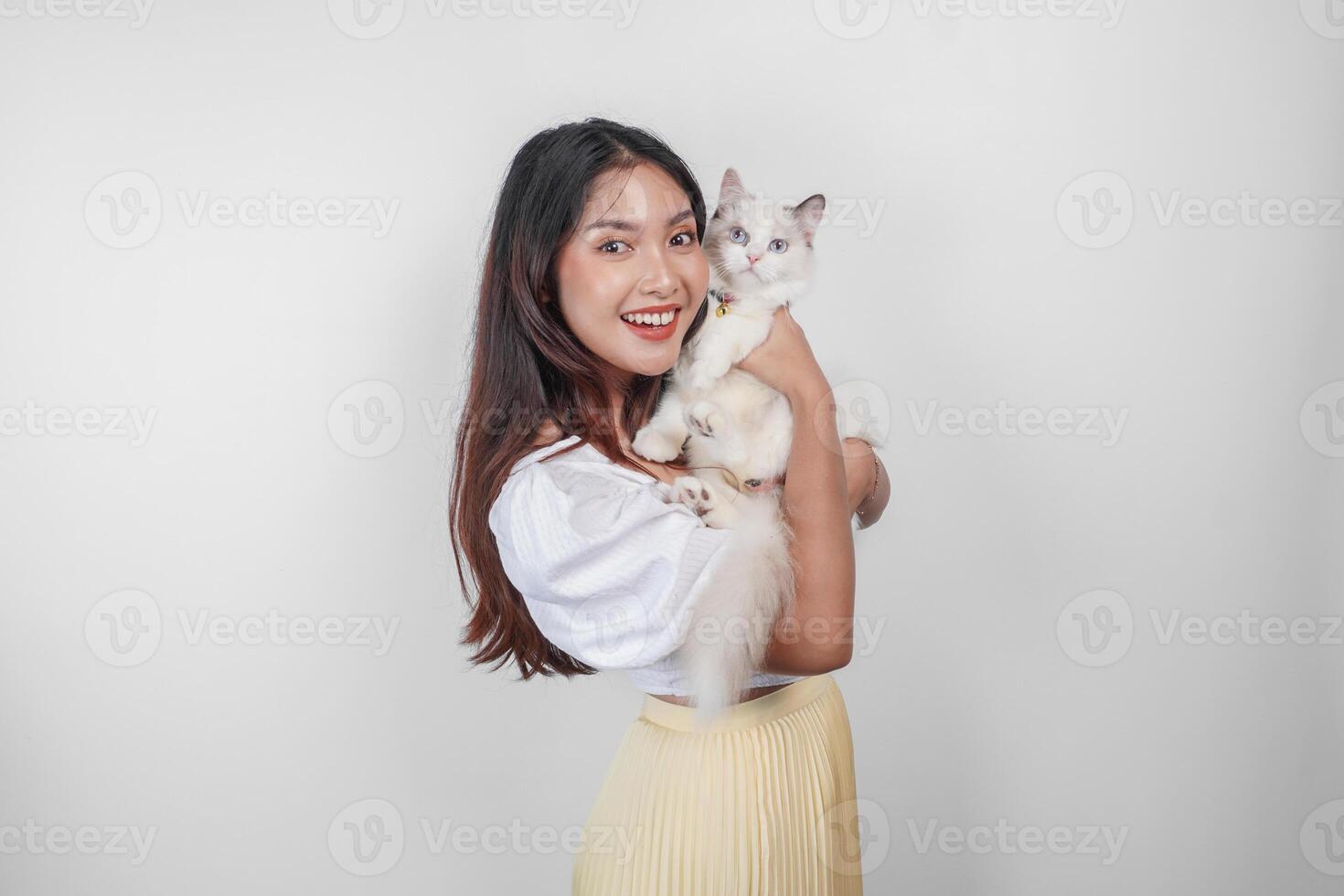 retrato de joven asiático mujer participación linda muñeca de trapo gato con azul ojos. hembra abrazando su linda largo pelo gatito aislado por blanco antecedentes. adorable Doméstico mascota concepto. foto