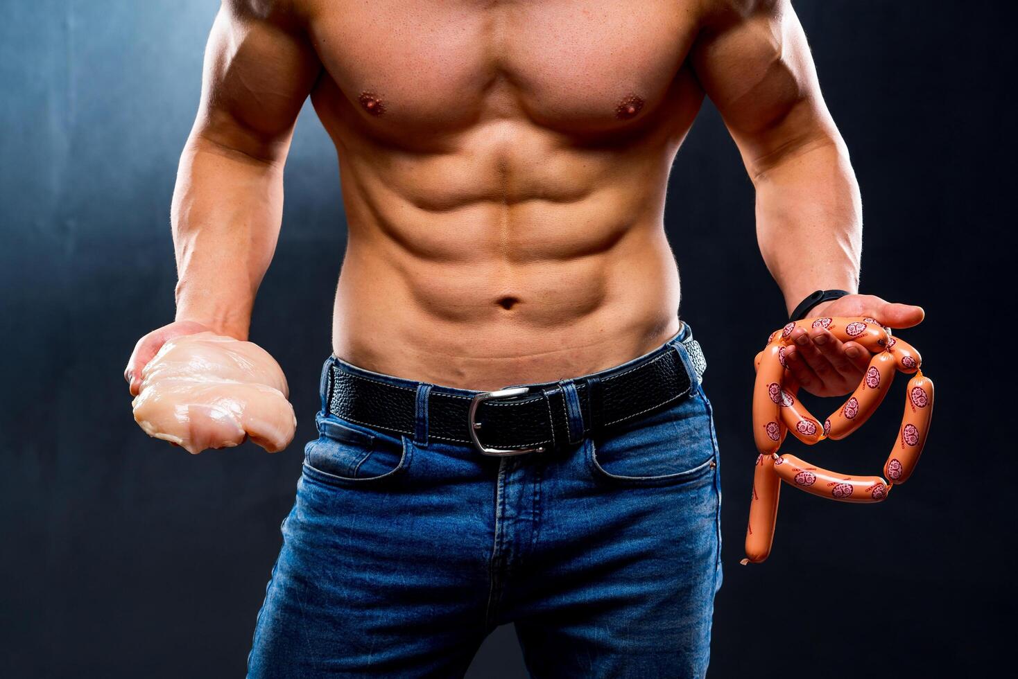 Athletic young sportsman holding chicken breasts and sausage. Dieting and sport nutrition, naked torso, muscular man. Cropped photo