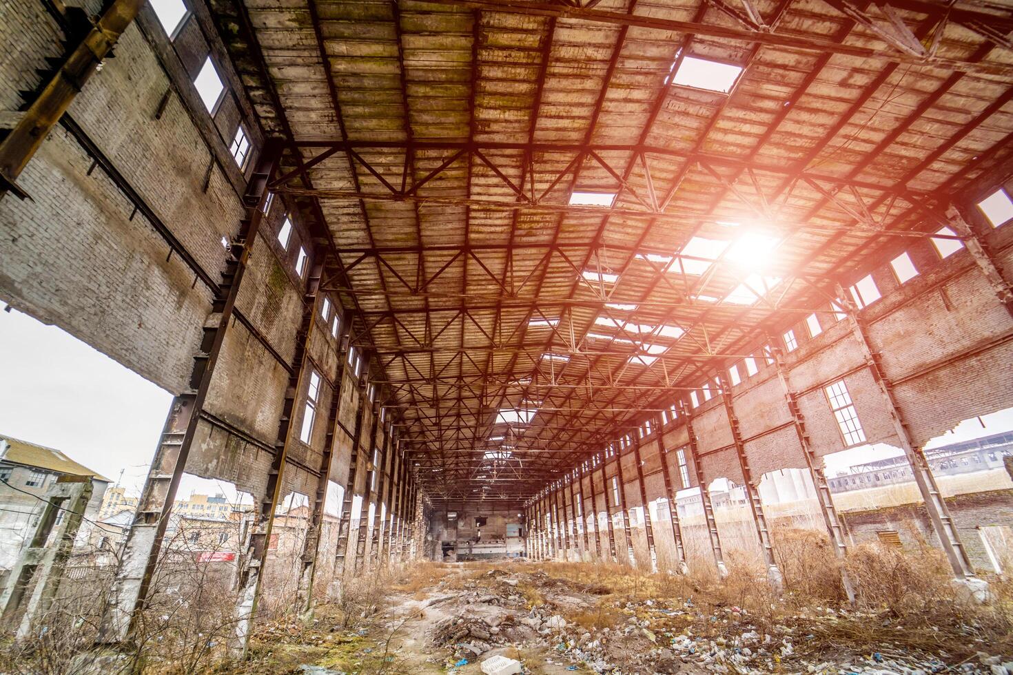 Interior of old factory building destroyed with holes in roof and walls. Ruins of industrial enterprise, pieces of debris crumbling in factory as result of economic crisis and earthquake photo