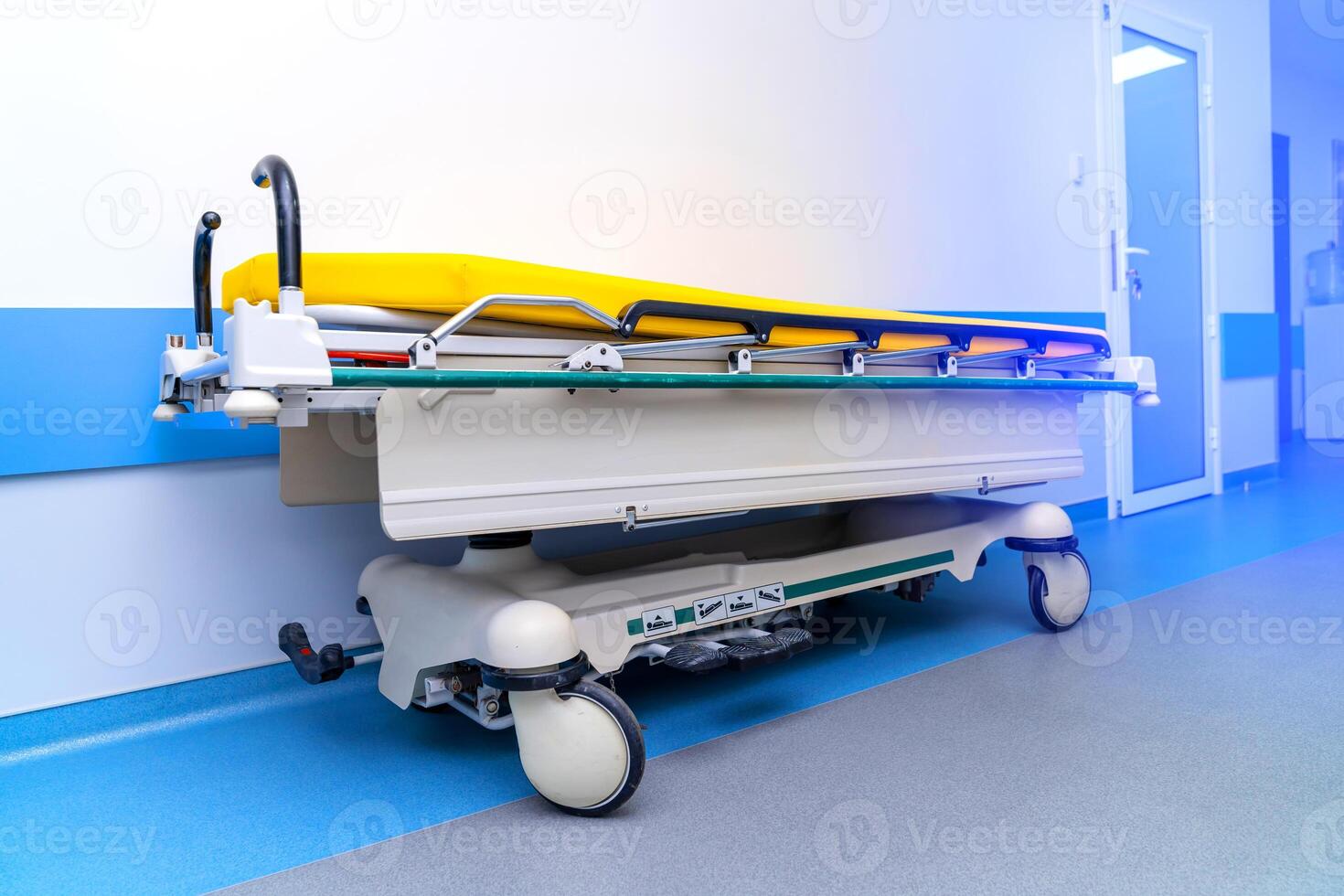Contemporary hospital bed on wheels with yellow mattres in light white and blue hall. photo