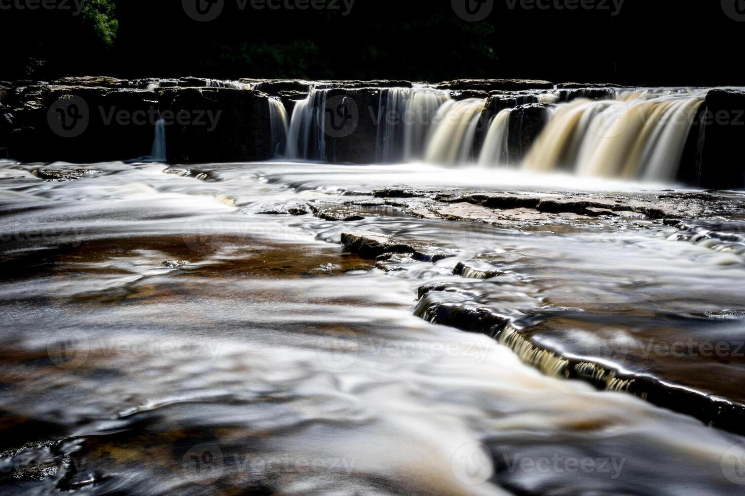 Silky smooth waterfall with a soft golden glow, captured in a serene natural setting. photo