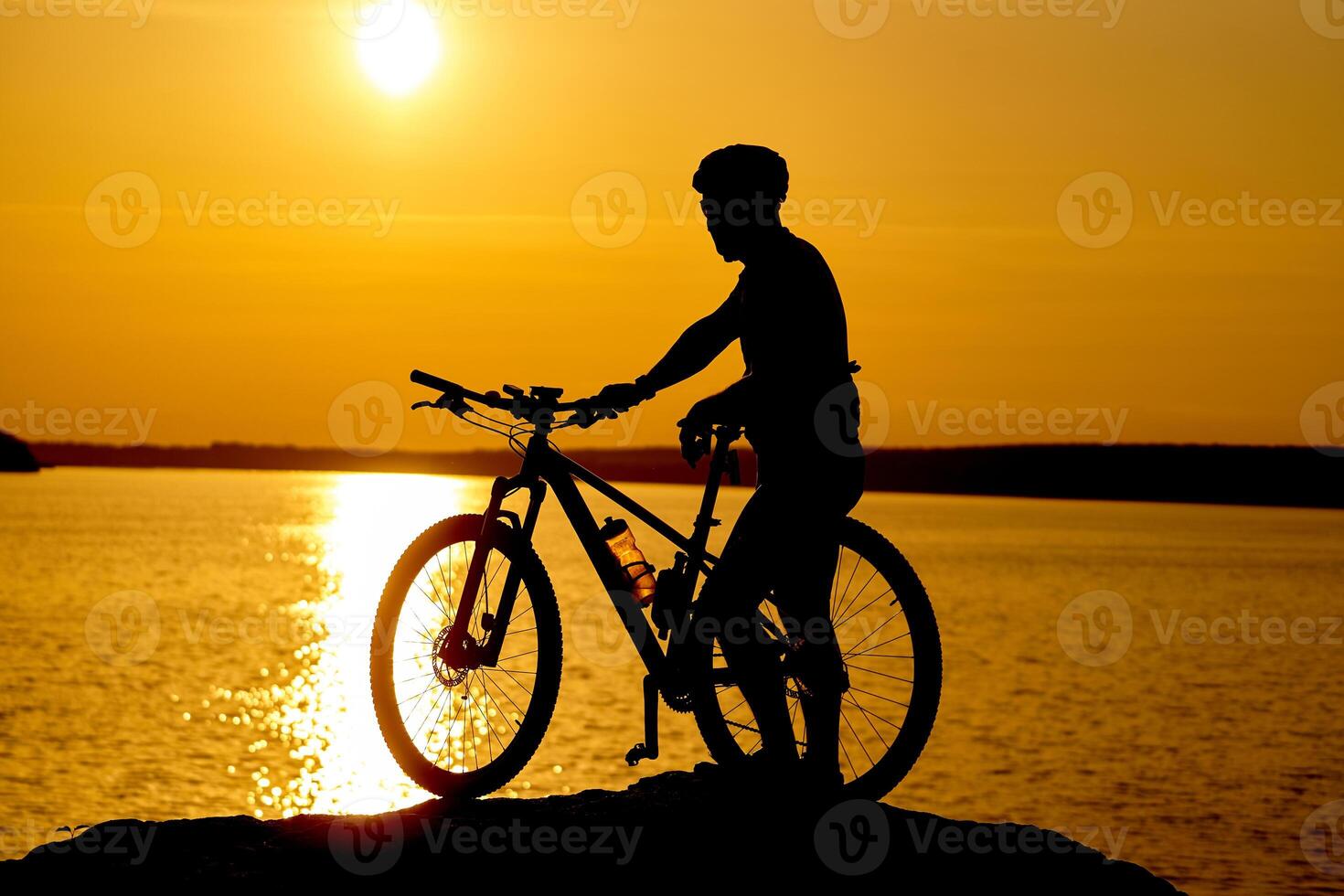 Silhouette of sportsman riding a bicycle on the beach. Colorful sunset cloudy sky in background photo