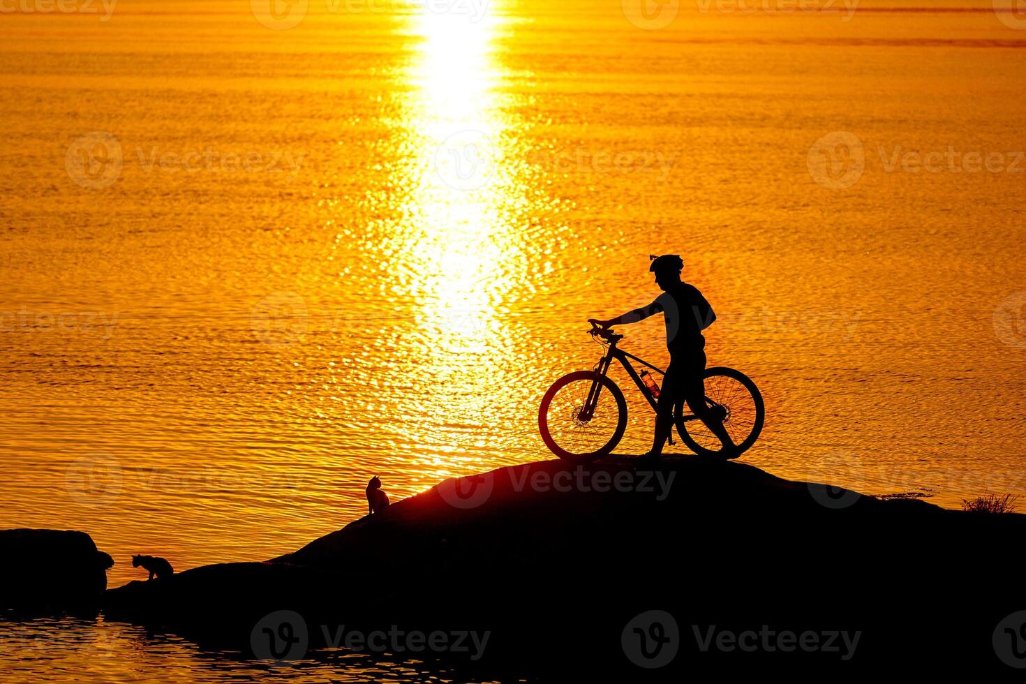 Silhouette of sportsman riding a bicycle on the beach. Colorful sunset cloudy sky in background photo