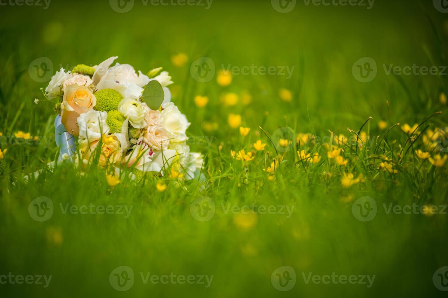 Flower bouquet of creamy roses on grass over the blurred background. Green grass and floral wedding bouquet with beautiful flowers. photo