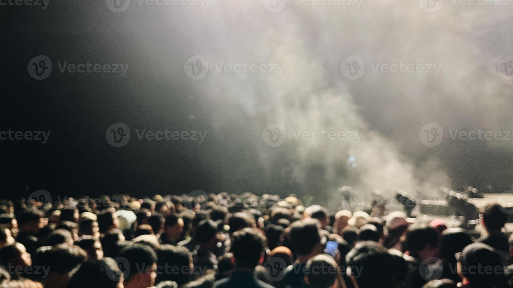 borroso imagen de un multitud a concierto con etapa luces y fumar foto