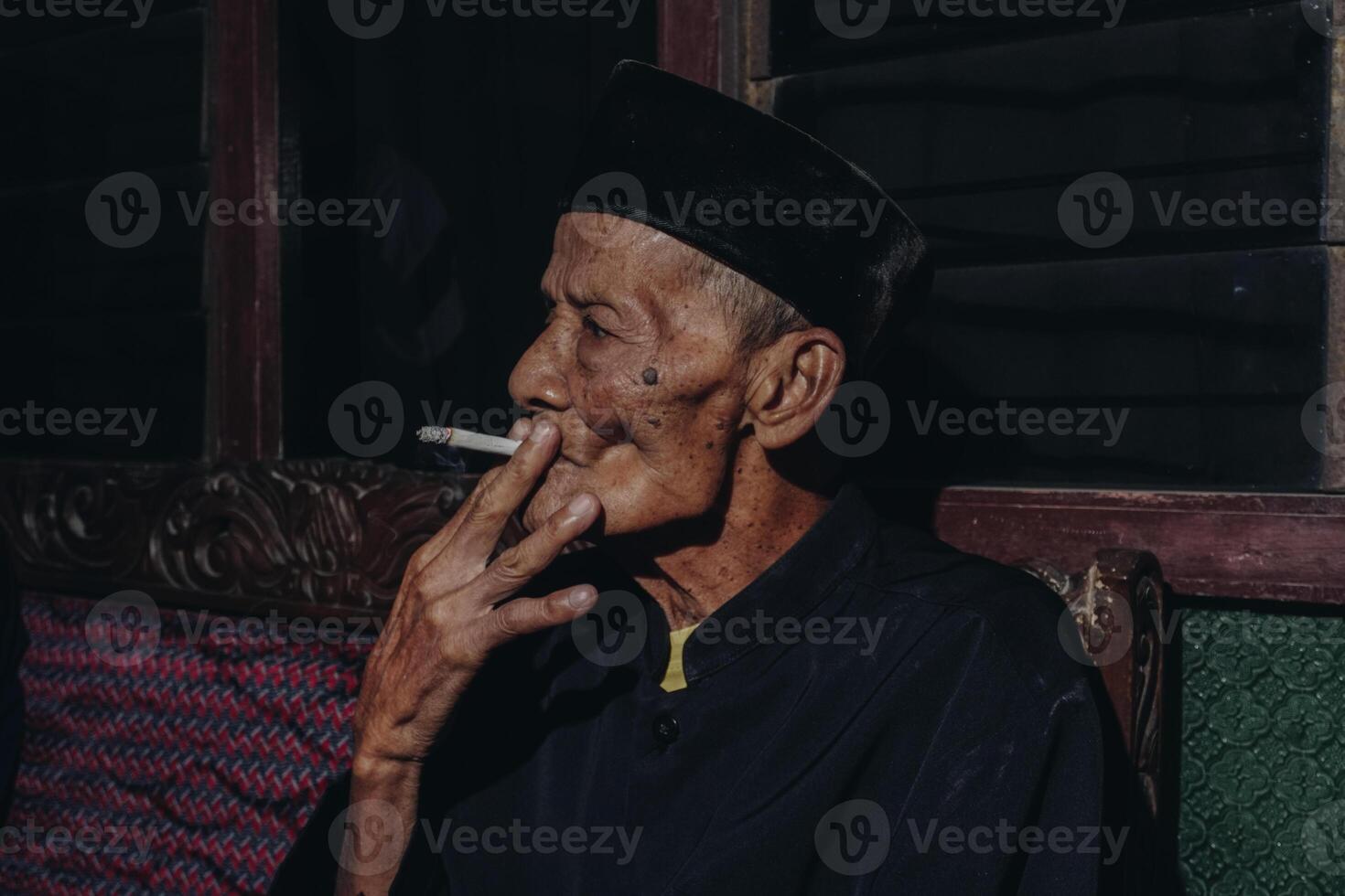 Portrait of an elderly Asian man smoking a cigarette. photo