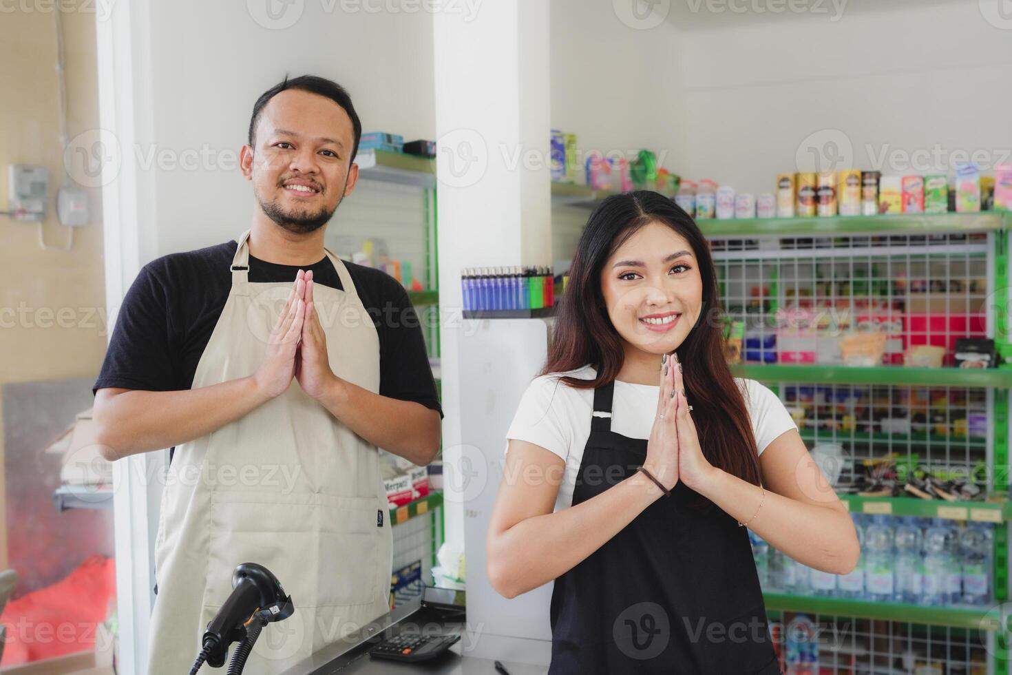 Friendly Asian woman as a cashier is handing a plastic bag to customer, wearing black apron photo