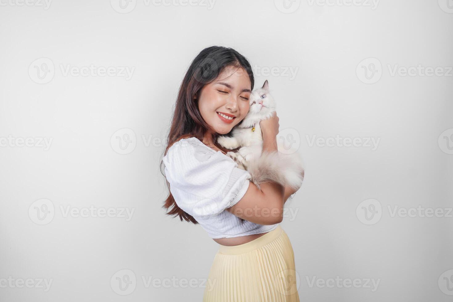 retrato de joven asiático mujer participación linda muñeca de trapo gato con azul ojos. hembra abrazando su linda largo pelo gatito aislado por blanco antecedentes. adorable Doméstico mascota concepto. foto